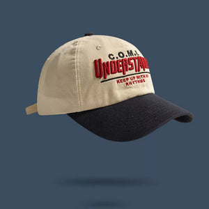 Embroidered statement baseball cap in beige with black brim and red text detail.