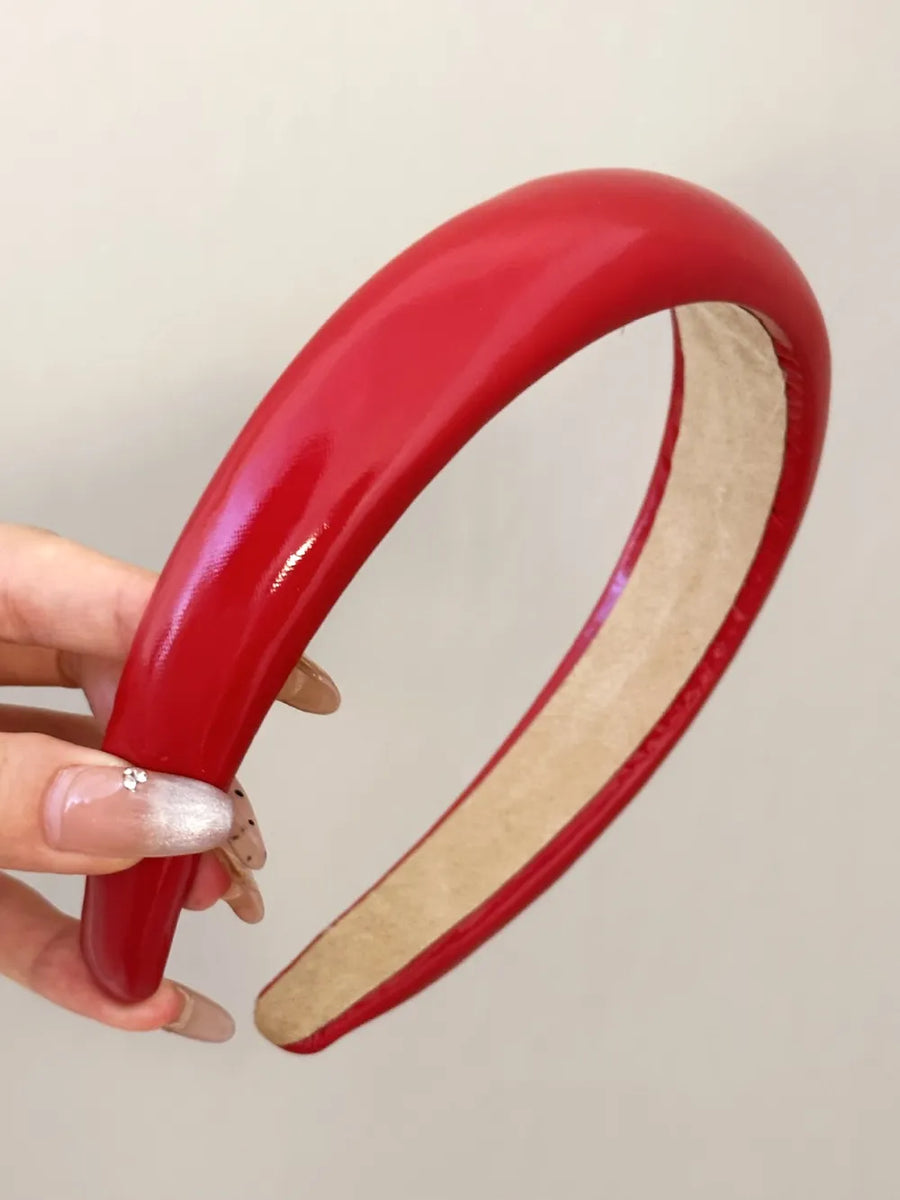 Glossy padded headband in deep red with a smooth finish.