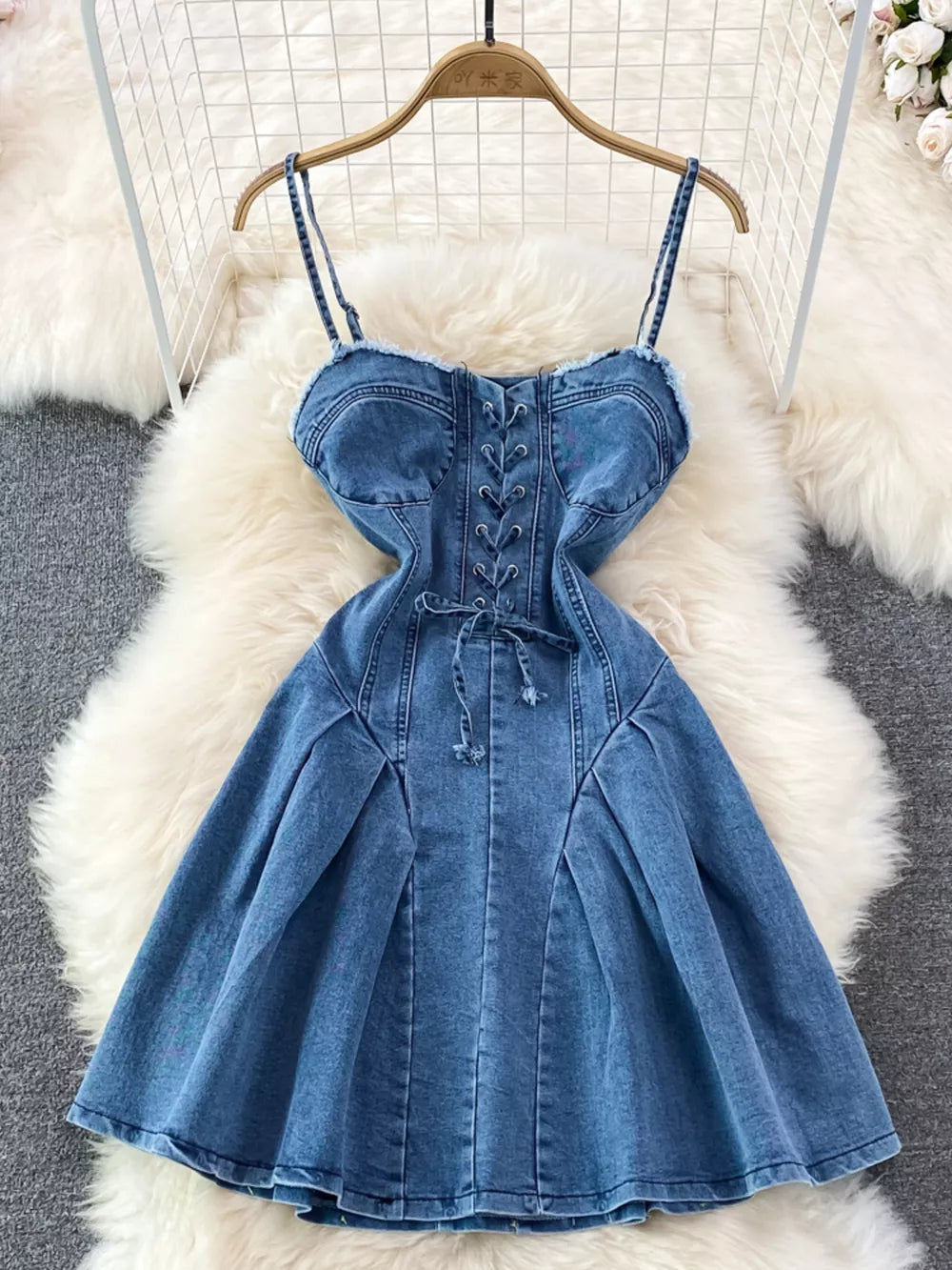 Blue denim A-line dress with lace-up corset detail and frayed hem.