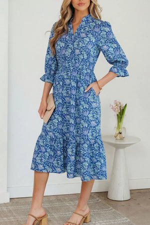 Blue floral cotton midi dress with cinched waist and frilled cuffs.