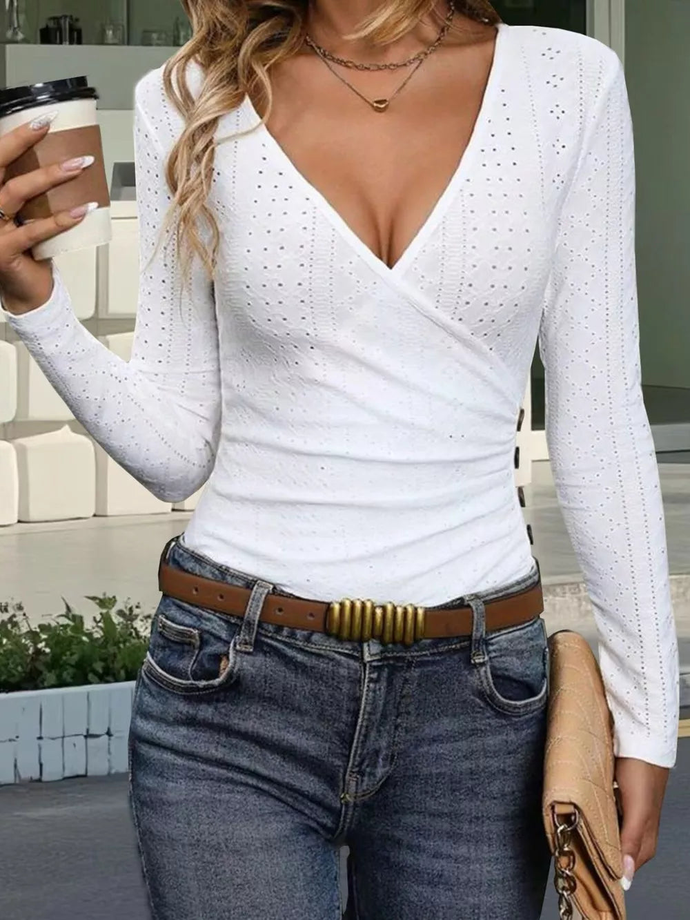 White eyelet wrap t-shirt with V-neck and decorative button detail, styled with jeans and a clutch.