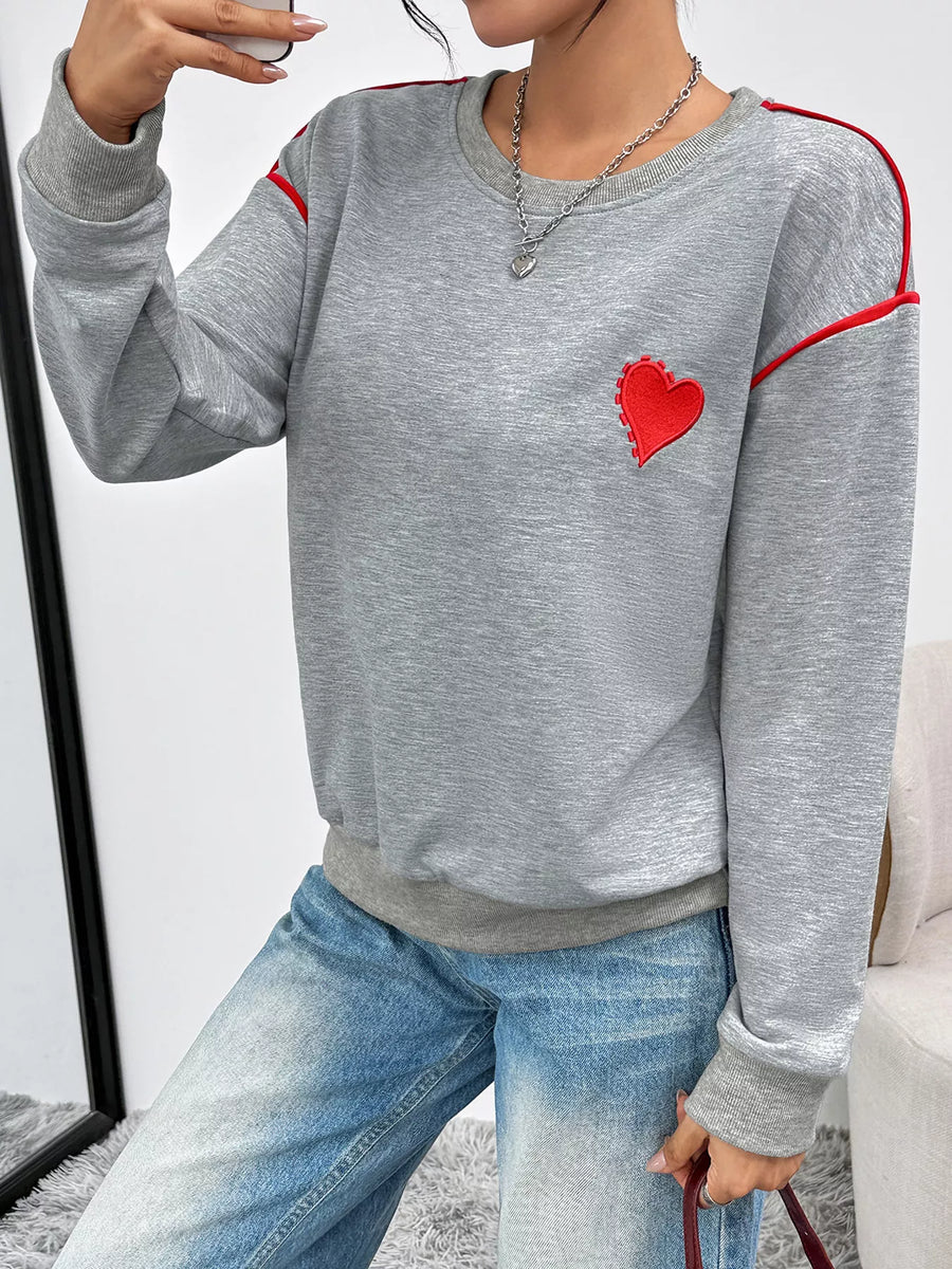 Gray sweatshirt with red heart embroidery and contrast piping detail.