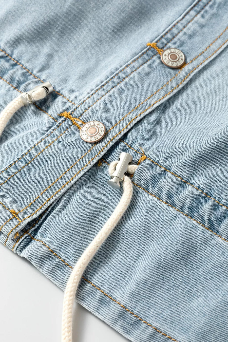 Light wash denim trucker jacket with adjustable draw-cord hem detail and button closures.