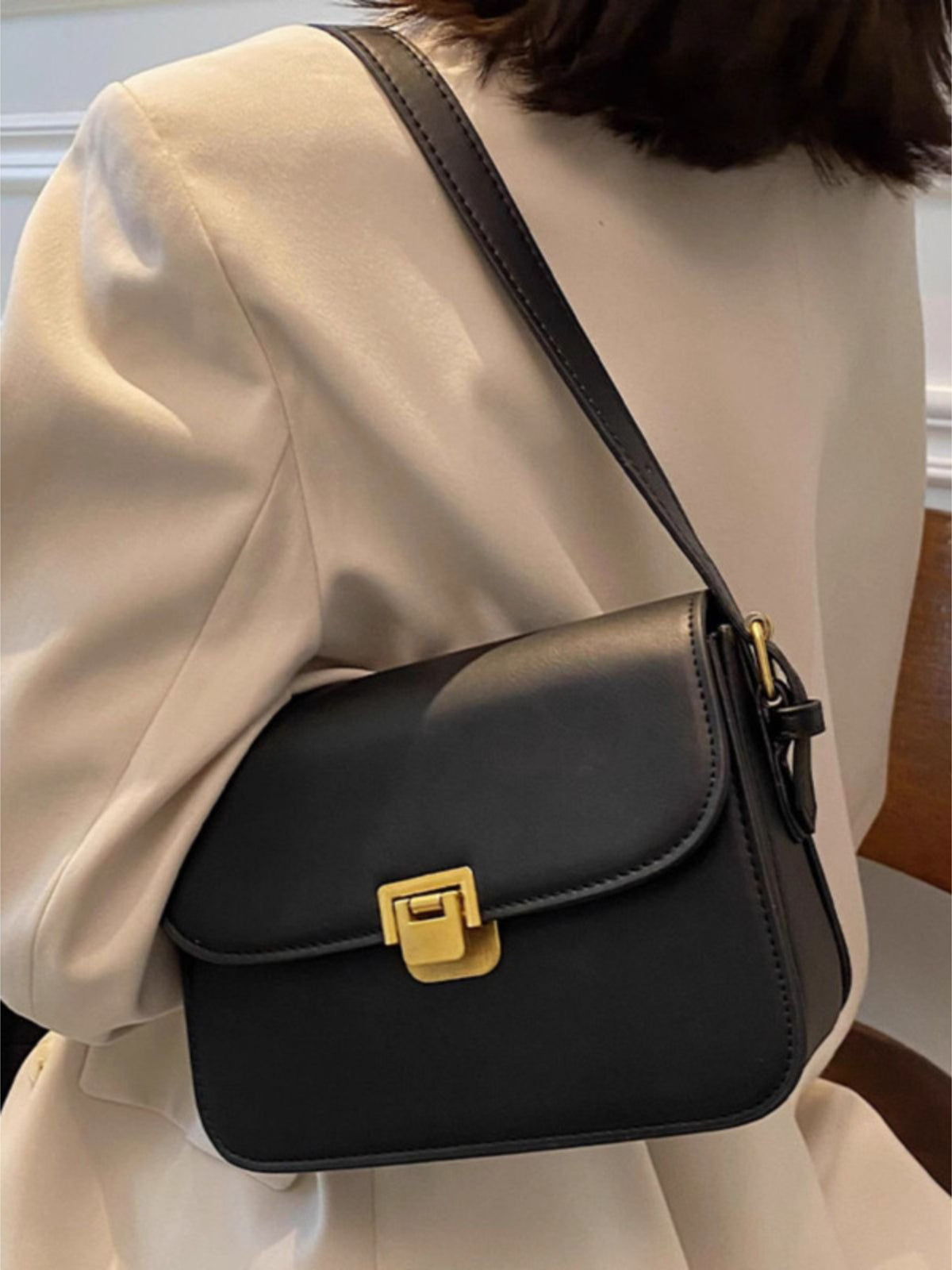 Black shoulder bag with gold buckle flap closure and adjustable strap