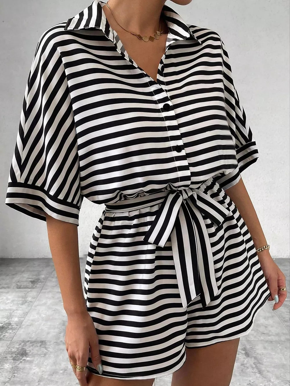 Black and white striped belted romper with collared button-front top and short sleeves.