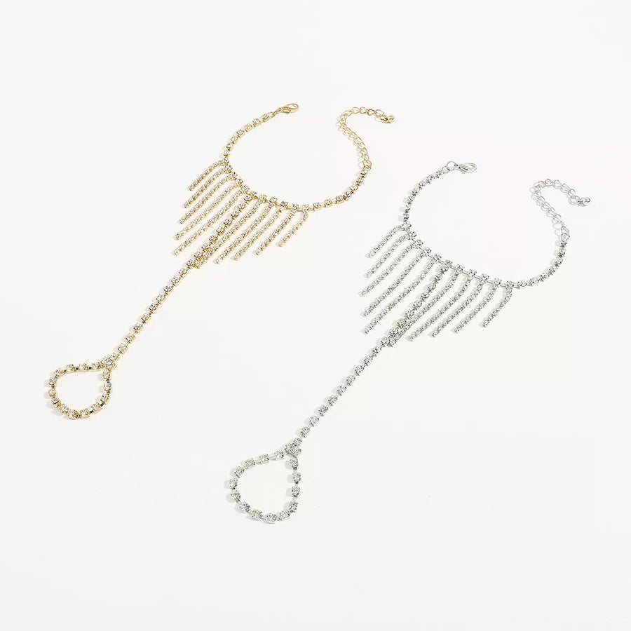 Rhinestone fringe hand chain bracelet in gold and white k with adjustable clasp and ring.