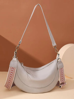 Light gray leather crescent crossbody bag with geometric strap