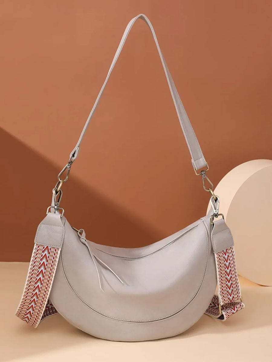 Light gray leather crescent crossbody bag with geometric strap