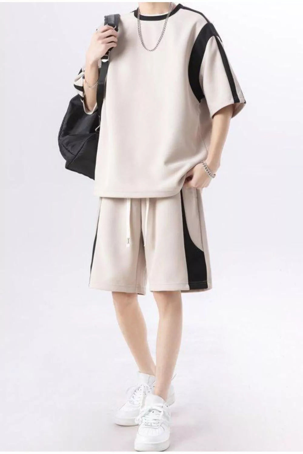 Beige shorts with black side panel and drawstring waist, paired with a matching short-sleeve top.