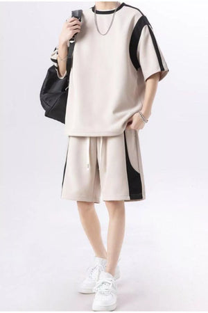 Beige shorts with black side panel and drawstring waist, paired with a matching short-sleeve top.