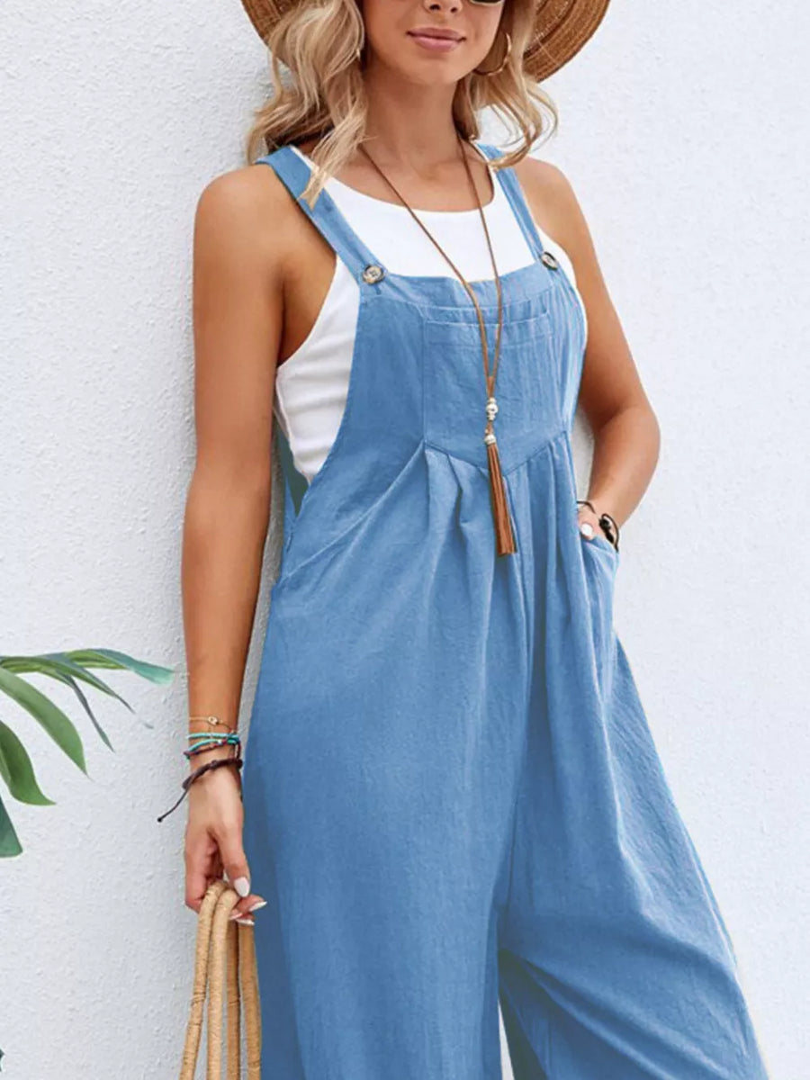 Light blue wide-leg romper with pockets and buttoned straps, styled with a white tank top.