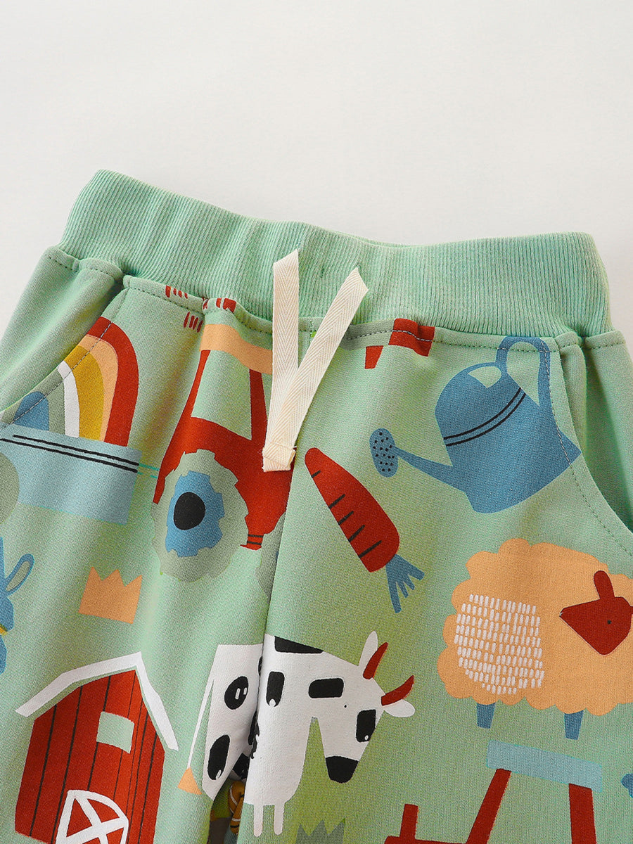 Light green cotton toddler shorts with farm animal print, rainbow, tractor, and watering can.