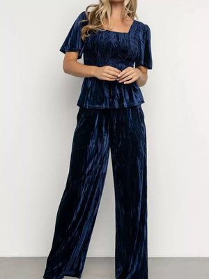 Navy blue velvet two-piece set with smocked bodice, flutter sleeves, and wide-leg pants.