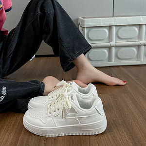 White leather sneakers with perforations and lace-up closure.