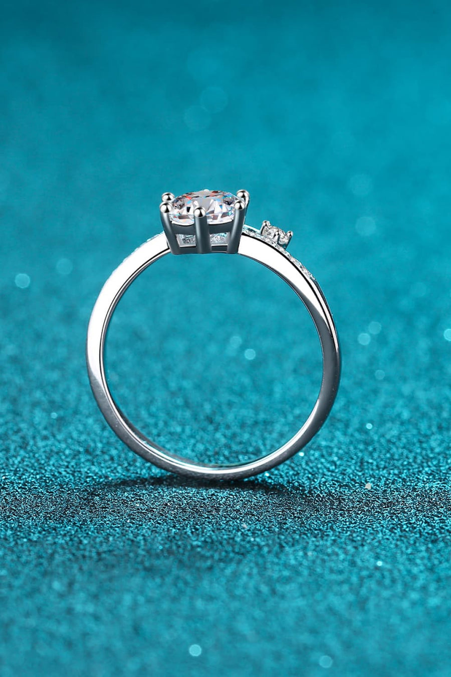 Silver moissanite bypass engagement ring with pavé band and solitaire center stone.