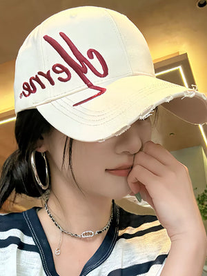White baseball cap with red embroidered script logo and distressed brim.
