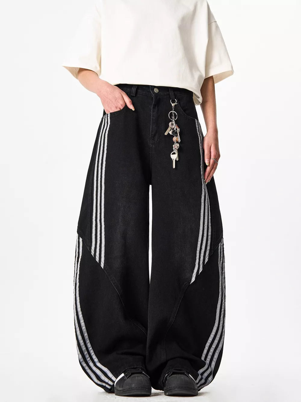 Black wide-leg jeans with white side stripes and a key chain detail.