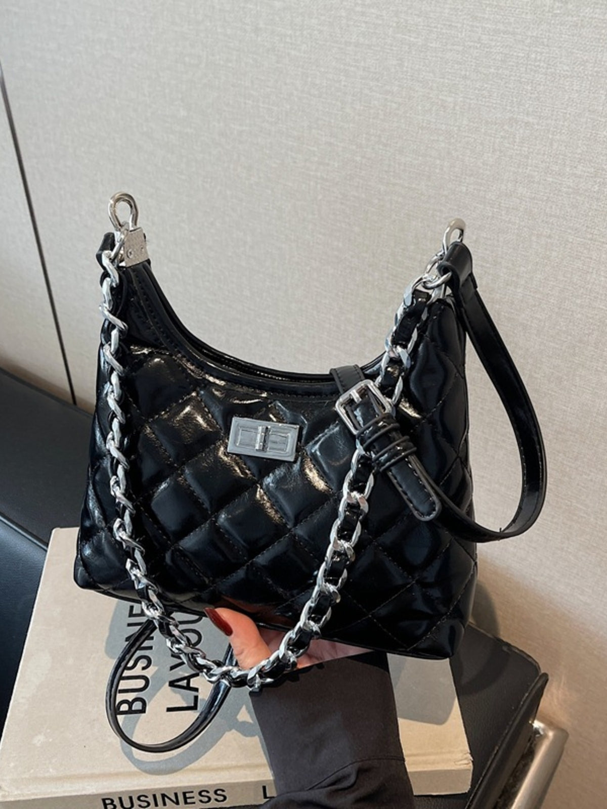Black quilted PU leather shoulder bag with silver chain strap and buckle detail.