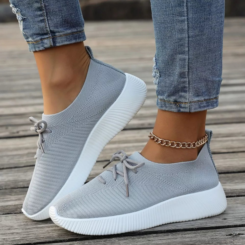 Gray breathable lace-up sneakers with white mid sole and white laces.