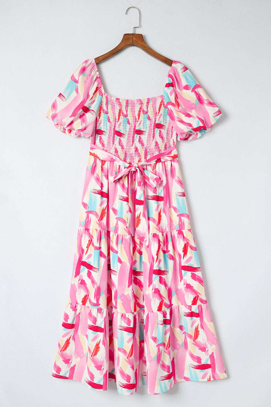 Blush pink midi dress with smocked bodice, balloon sleeves, tiered skirt, and brushstroke print.