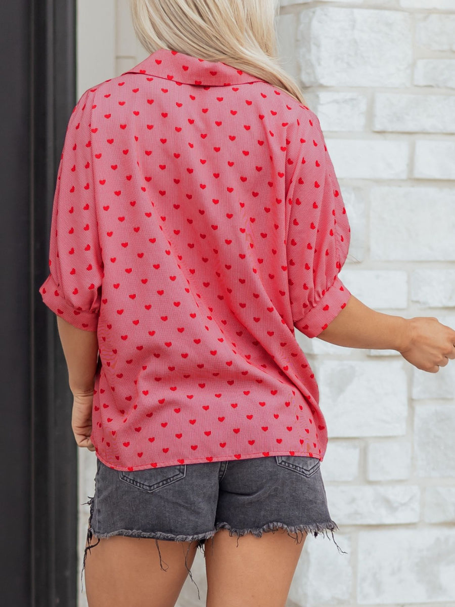 Pink button-down shirt with red heart pattern, cuffed sleeves, and classic collar.