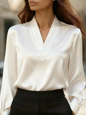White satin blouse with V-neck and long sleeves, styled with black pants.