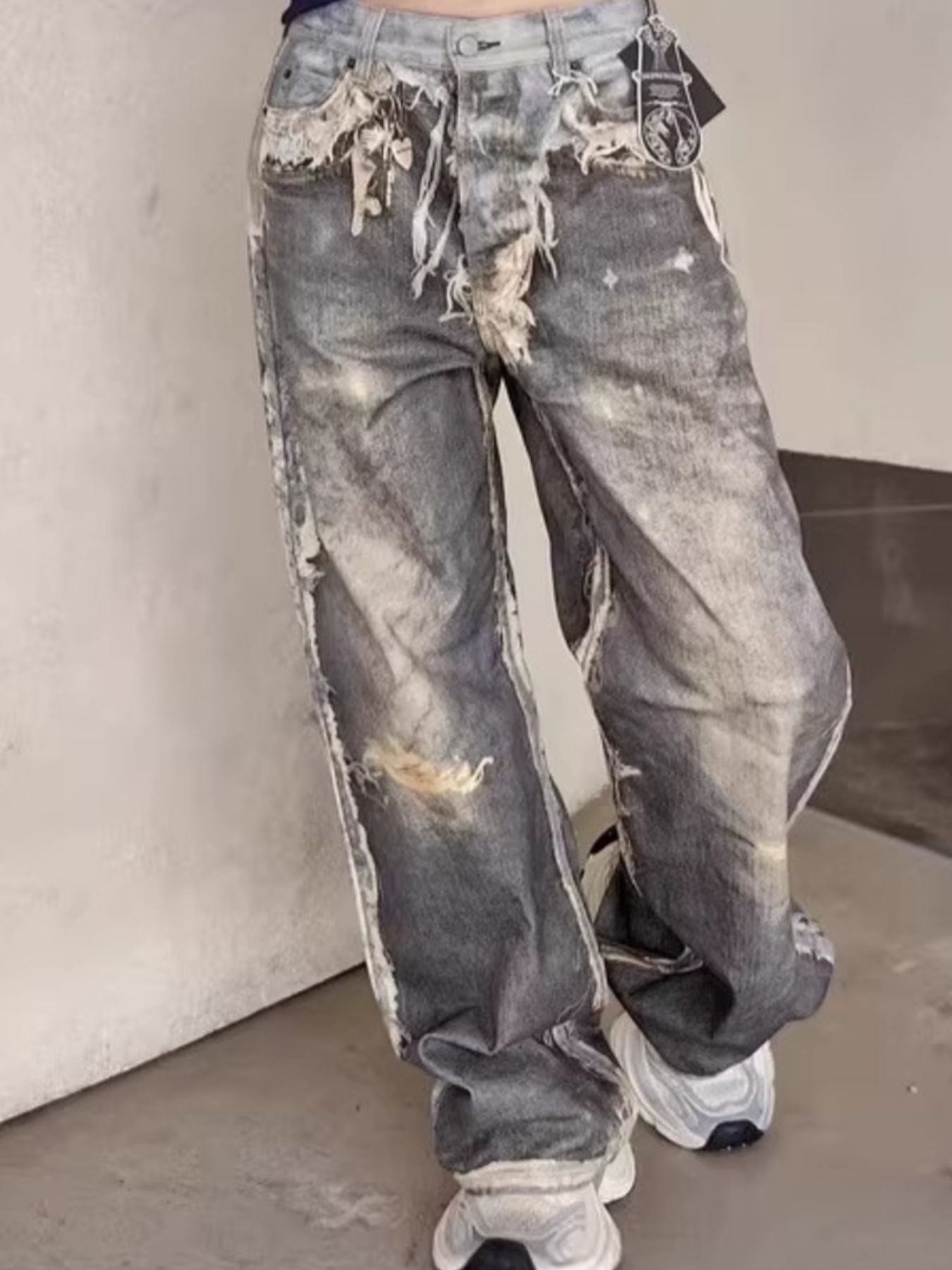 Heavily distressed wide-leg men's jeans in grey denim with baggy fit and frayed details.