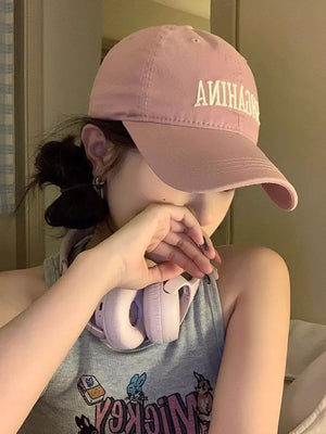Pink cotton baseball cap with mirrored white embroidered lettering and curved brim.