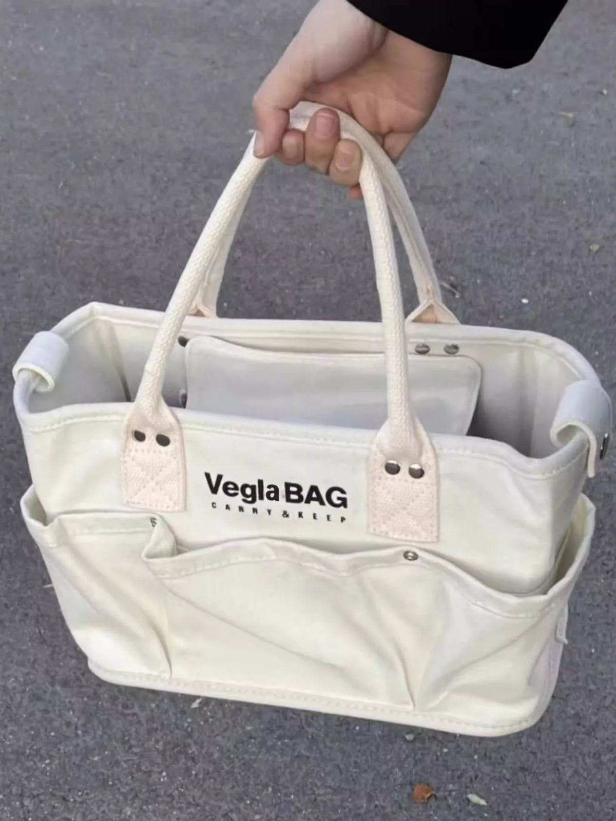 Beige canvas shopper bag with multiple exterior pockets and rope handles.
