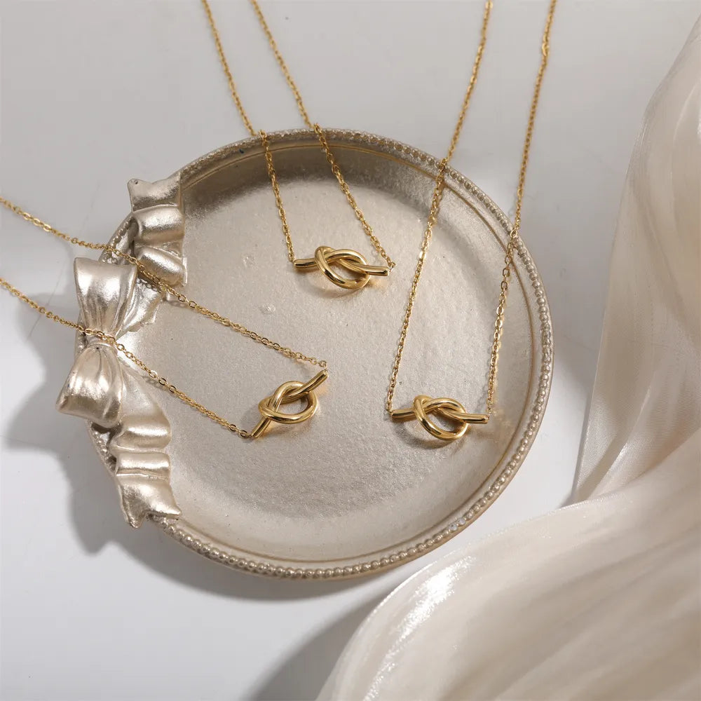 Gold knot pendant necklaces on a decorative tray
