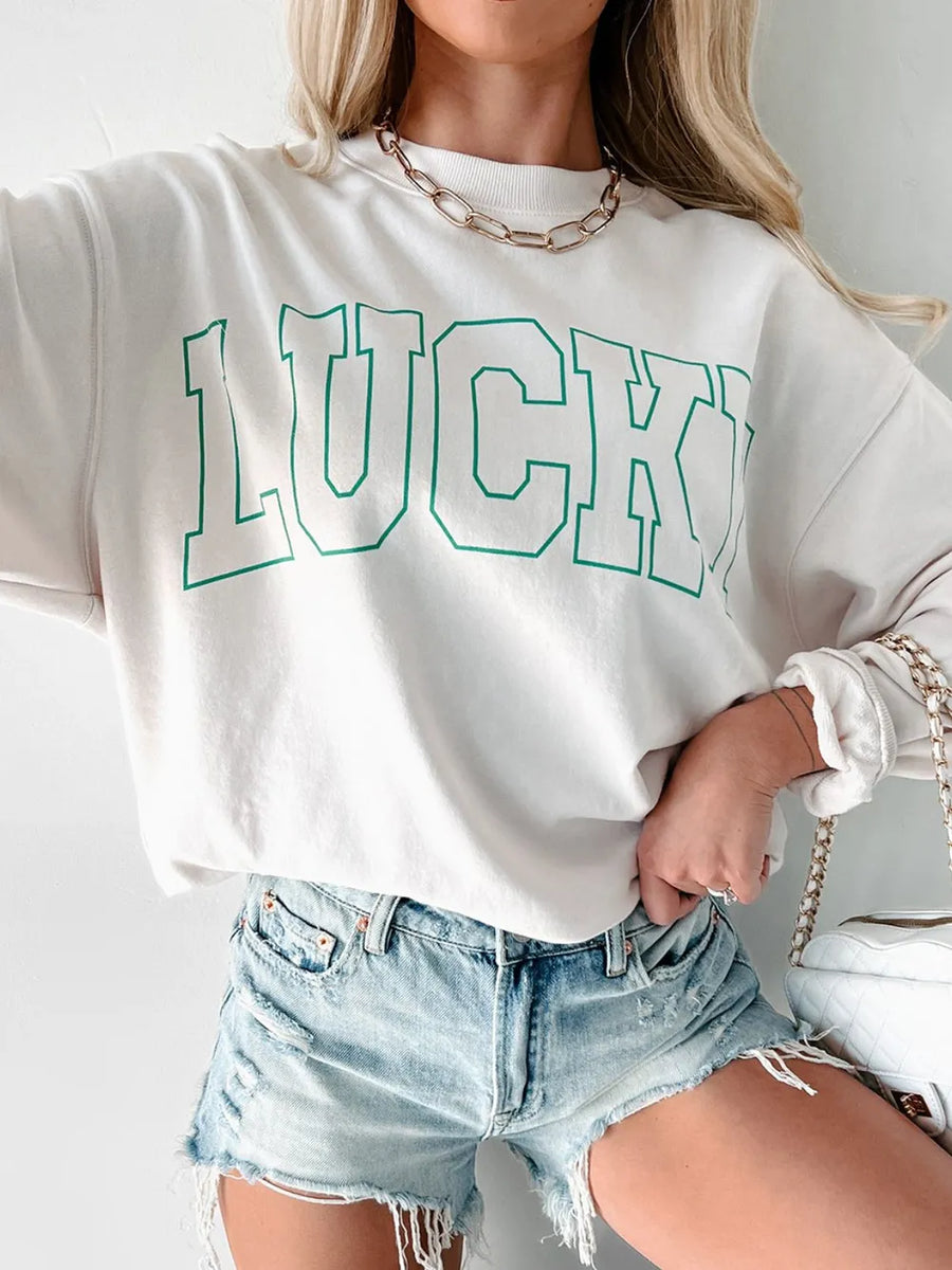 White sweatshirt with green varsity "LUCKY" graphic, crewneck, long sleeves.