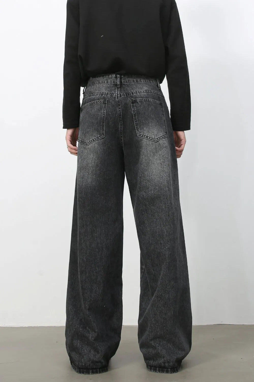 Exaggerated wide-leg dark wash denim trousers with a relaxed fit and distressed details.