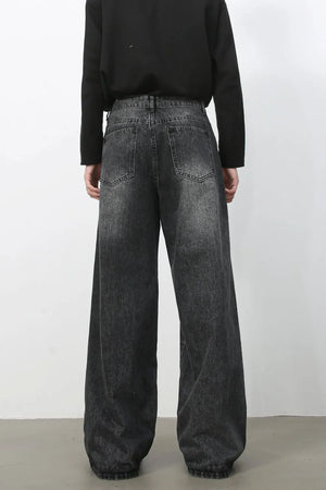 Exaggerated wide-leg dark wash denim trousers with a relaxed fit and distressed details.