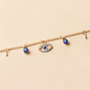 Gold evil eye charm necklace with blue teardrop accents and crystal details