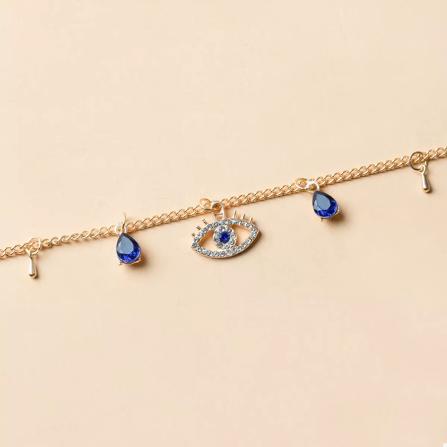Gold evil eye charm necklace with blue teardrop accents and crystal details