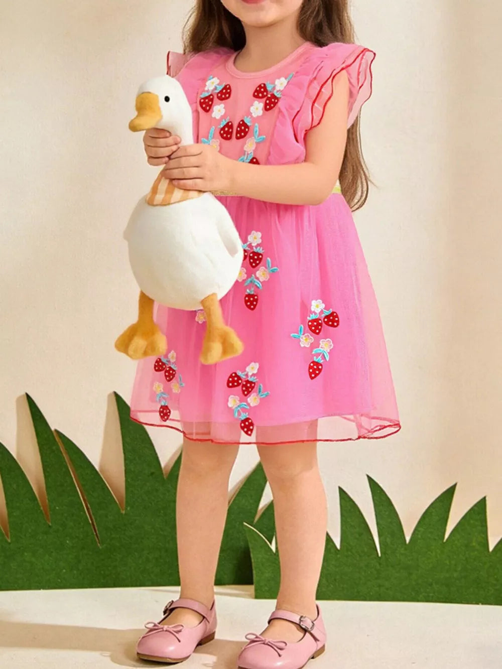 Pink tulle toddler dress with embroidered strawberries and ruffled sleeves.
