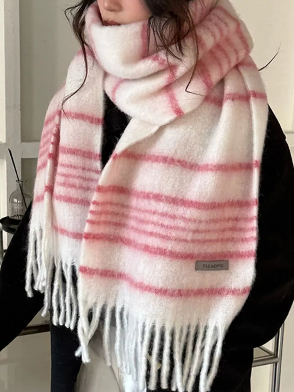 Chic pink and white striped scarf with fringe hem and cozy texture.