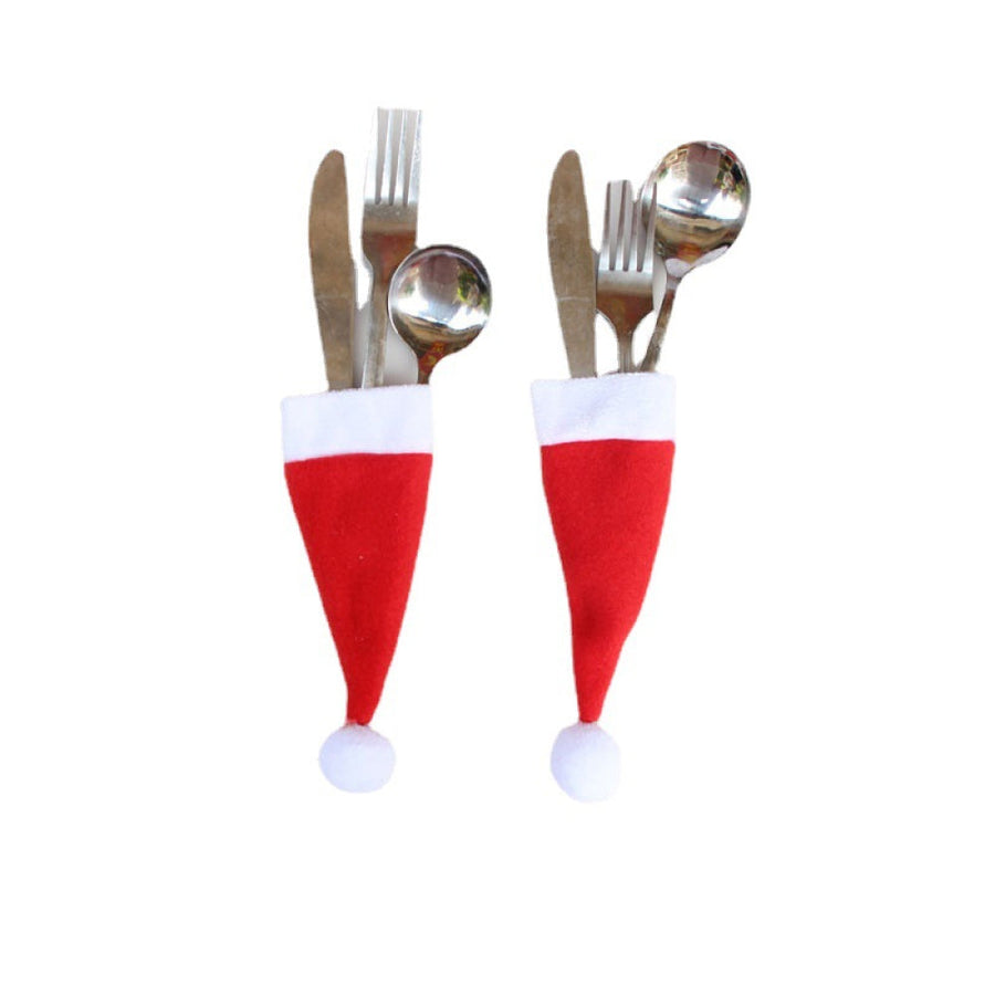 Red Santa hat cutlery holders with white trim and pom-poms, holding silverware.
