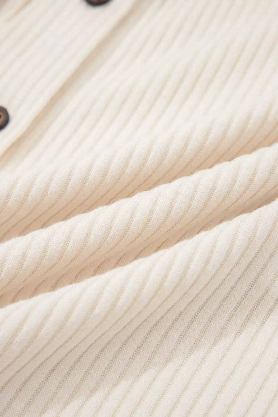 Ribbed cream button-down shirt with contrast buttons and animal print detail.
