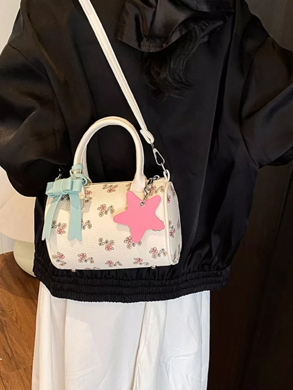 Charming floral mini crossbody bag with a pink star charm and blue bow detail.