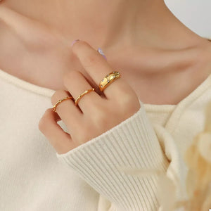Gold rings with zircon studs and twisted bands, worn on a woman's hand.