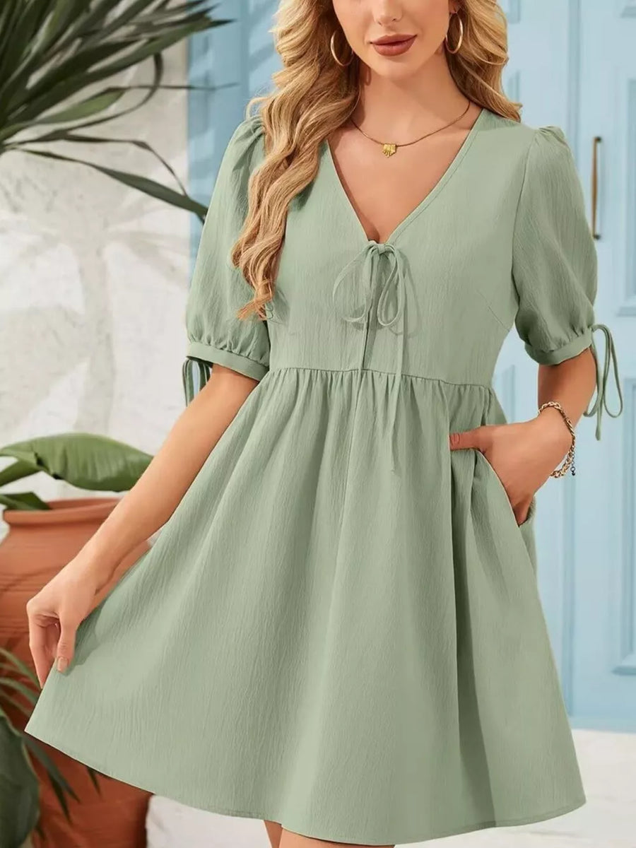 Light green mini dress with puff sleeves, tie neck, and tie cuffs.
