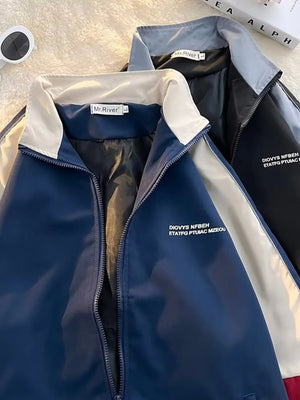 Men's blue zip-up track jacket with white collar and cream accents, featuring text detail.