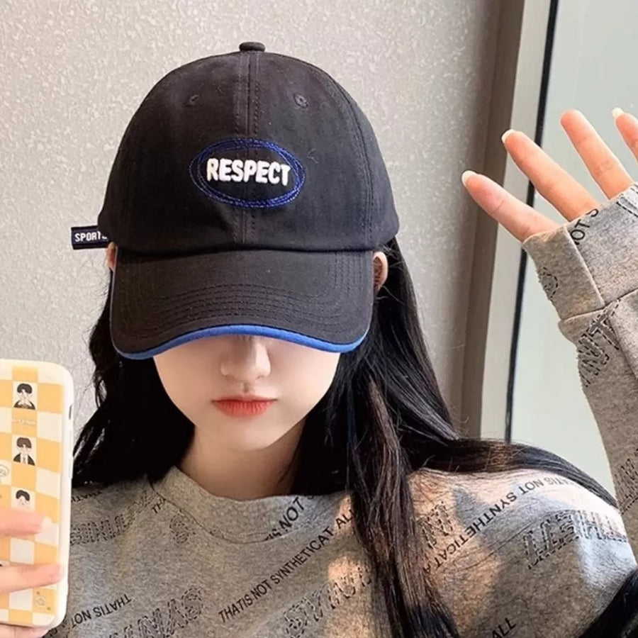 Black baseball cap with embroidered oval "RESPECT" patch and blue brim detail.