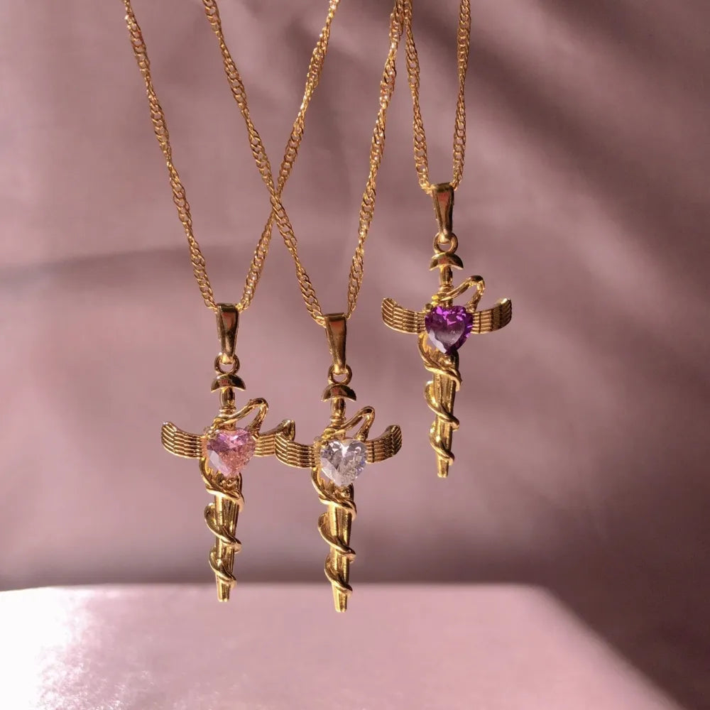 18K gold-plated necklaces with cross charm pendants featuring heart-shaped gemstones in pink, clear, and purple.