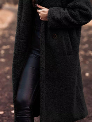 Black teddy bear longline coat with button detail and pockets.