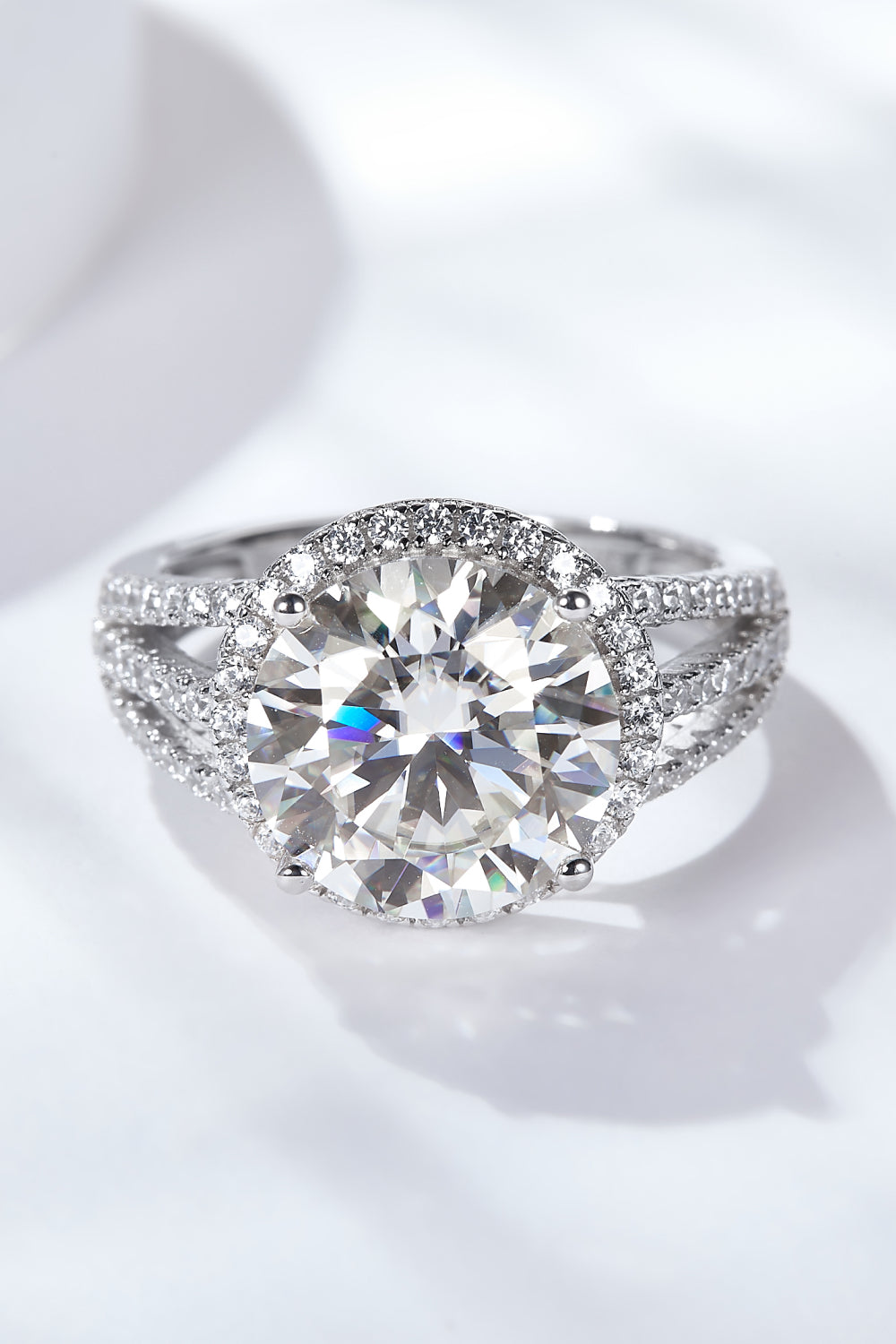 Silver split shank halo engagement ring with large center stone and pavé band.