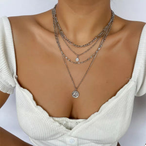 Silver layered coin pendant necklace with cubic zirconia accents.