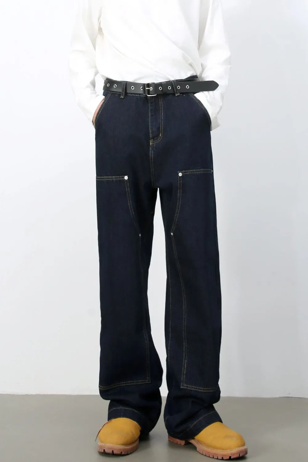 Dark wash denim carpenter pants with a wide, relaxed fit and contrast stitching.