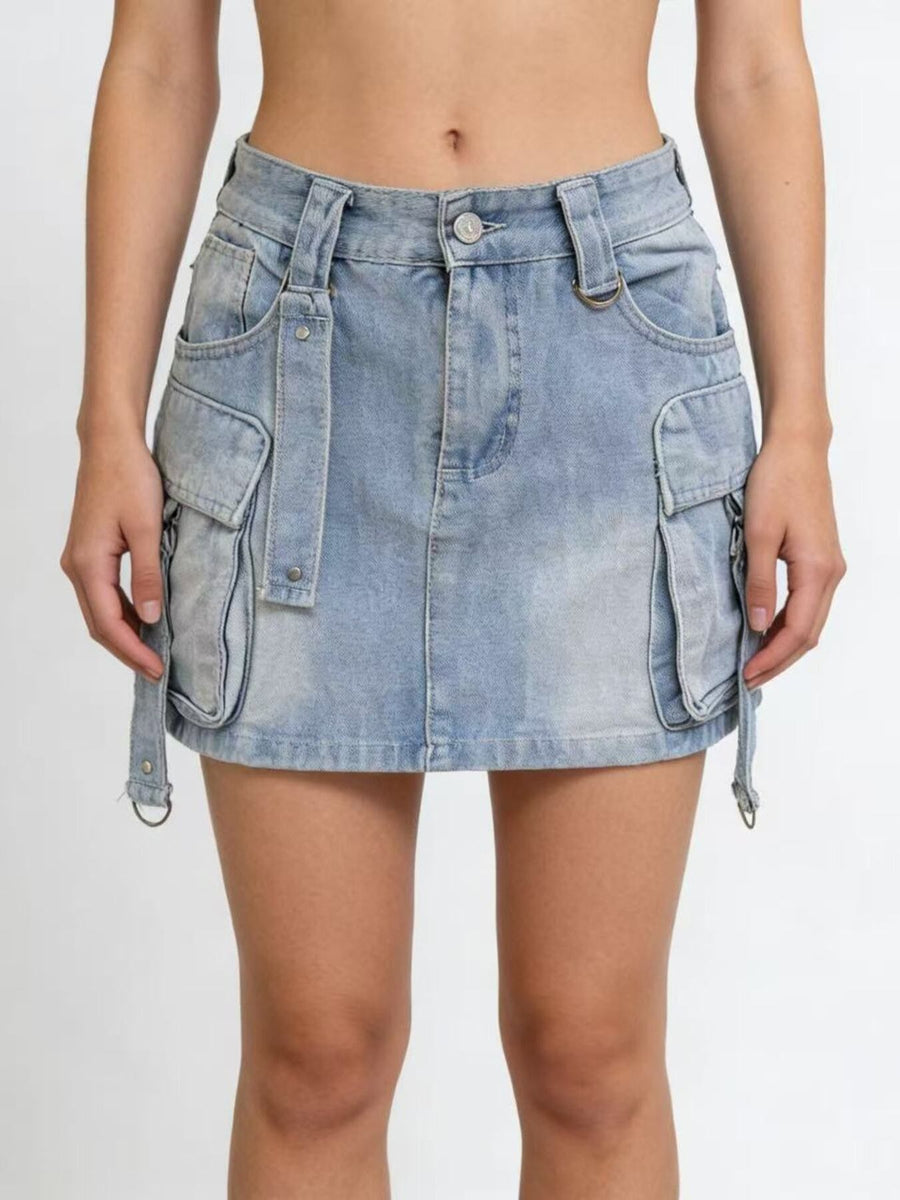 Plus size light wash denim cargo skirt with button closure and strap details.